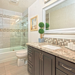 Porcelain tile tub surround, glass tile insets, granite countertop, dark cabinets, porcelain floor tiles.
